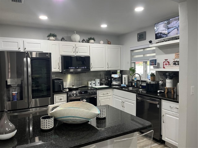 kitchen featuring sink, appliances with stainless steel finishes, dark stone countertops, backsplash, and white cabinets