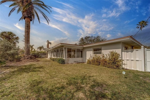 back of property with a sunroom and a lawn