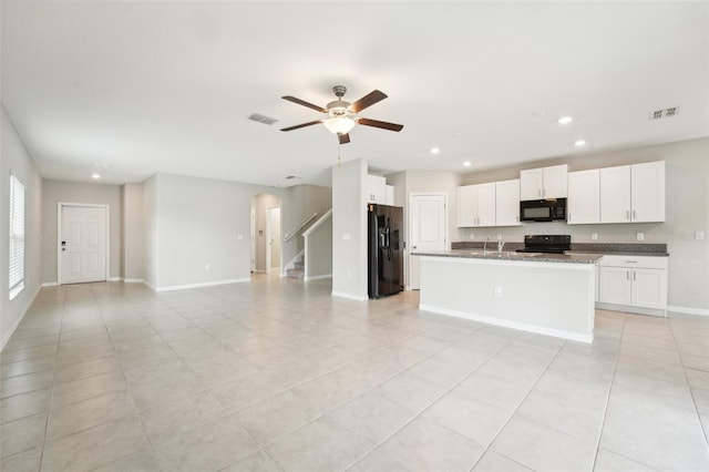 kitchen with light tile patterned floors, ceiling fan, a kitchen island with sink, white cabinetry, and black appliances