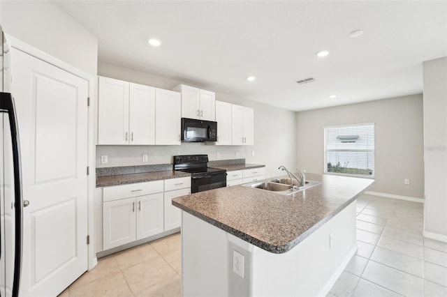 kitchen with sink, white cabinetry, light tile patterned floors, an island with sink, and black appliances