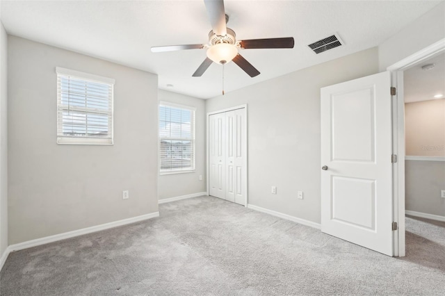 unfurnished bedroom with light colored carpet, a closet, and ceiling fan