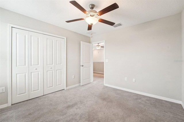 unfurnished bedroom featuring ceiling fan, light colored carpet, and a closet