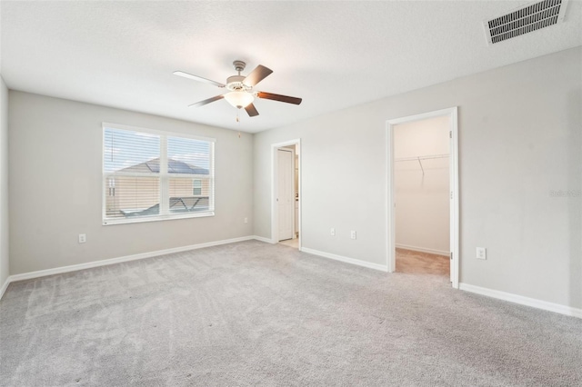 empty room with a textured ceiling, light colored carpet, and ceiling fan