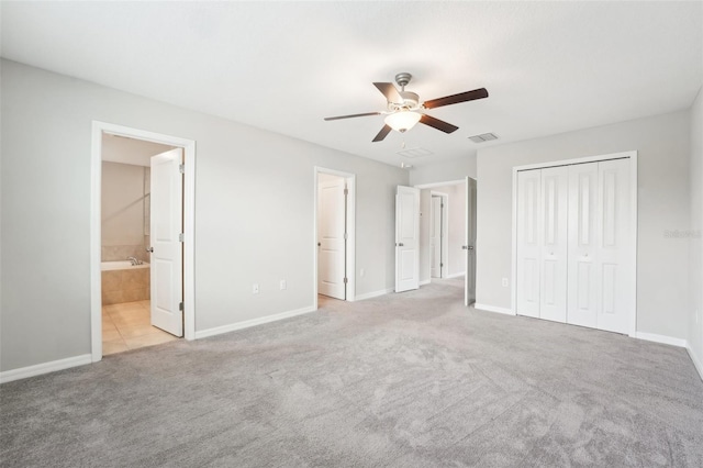 unfurnished bedroom with ceiling fan, a closet, connected bathroom, and light carpet