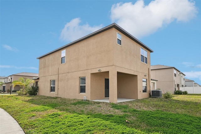 back of house featuring a yard, central AC unit, stucco siding, and a patio