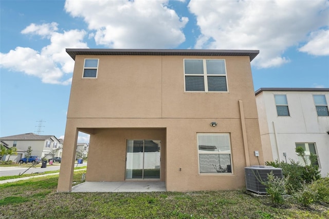 rear view of property featuring a patio area, stucco siding, a lawn, and central AC unit