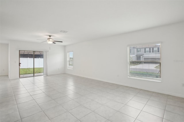 spare room featuring light tile patterned floors, visible vents, baseboards, and a ceiling fan