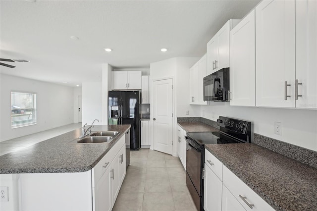 kitchen with light tile patterned flooring, a sink, white cabinetry, black appliances, and dark countertops