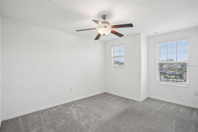 carpeted spare room featuring ceiling fan and baseboards