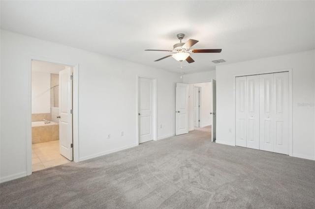 unfurnished bedroom featuring visible vents, ensuite bath, ceiling fan, carpet, and a closet