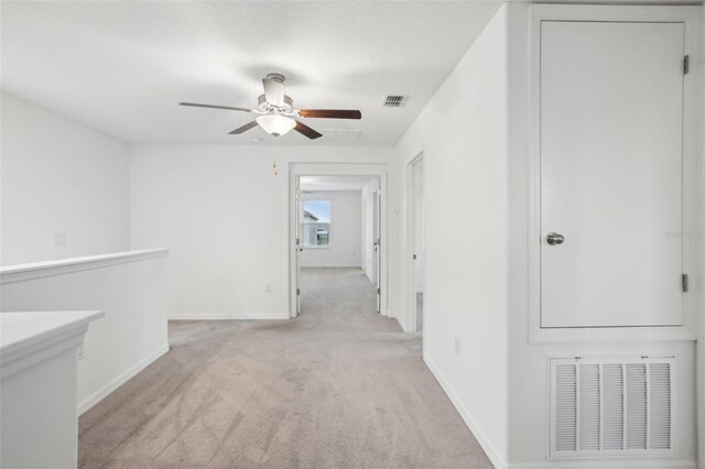 hall featuring light carpet, visible vents, and baseboards