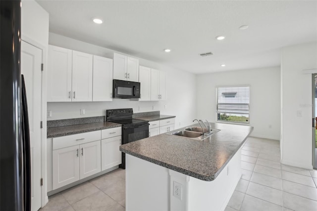 kitchen featuring visible vents, dark countertops, black appliances, white cabinetry, and a sink