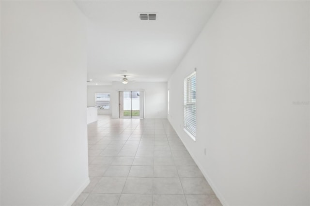 corridor with visible vents, baseboards, and light tile patterned floors