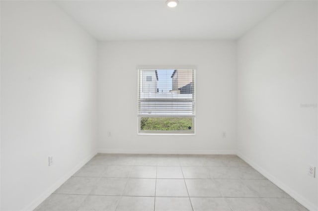 spare room featuring light tile patterned floors and baseboards