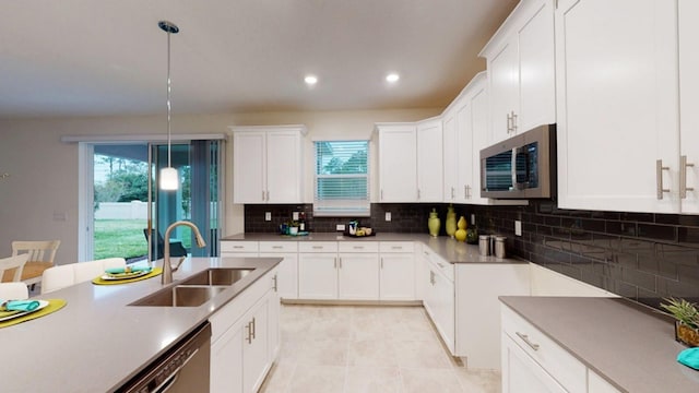 kitchen with hanging light fixtures, white cabinetry, appliances with stainless steel finishes, and sink