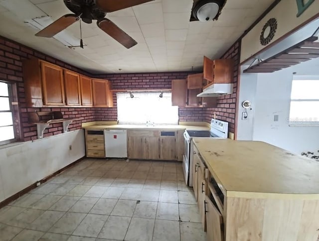 kitchen with brick wall, a healthy amount of sunlight, and white appliances