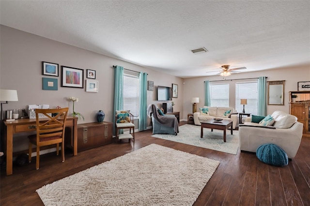 living room with ceiling fan, dark hardwood / wood-style floors, and a textured ceiling