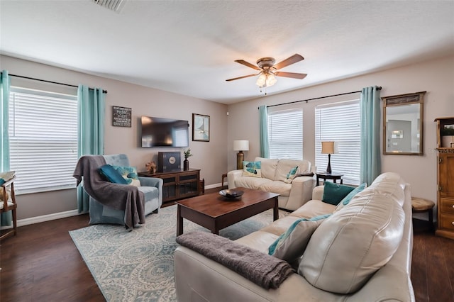 living room featuring dark wood-type flooring, ceiling fan, and a wealth of natural light