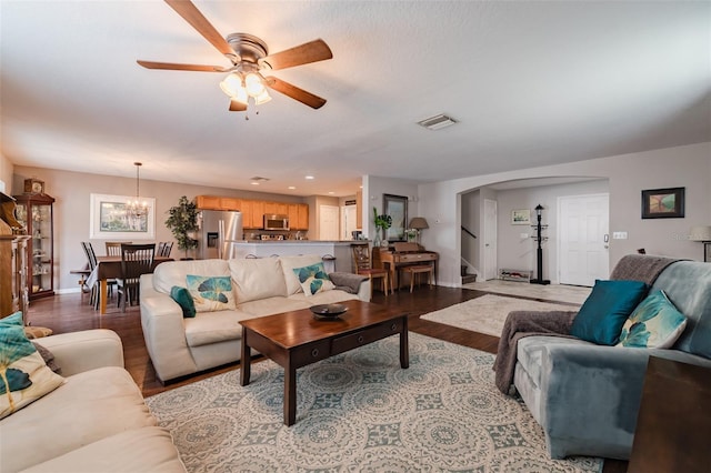 living room featuring ceiling fan with notable chandelier and light wood-type flooring