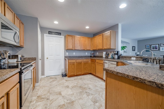 kitchen featuring sink, kitchen peninsula, a textured ceiling, and appliances with stainless steel finishes