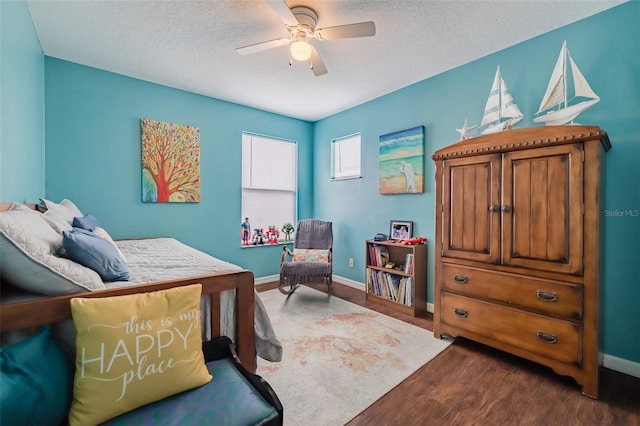 bedroom featuring dark wood-type flooring, ceiling fan, and a textured ceiling