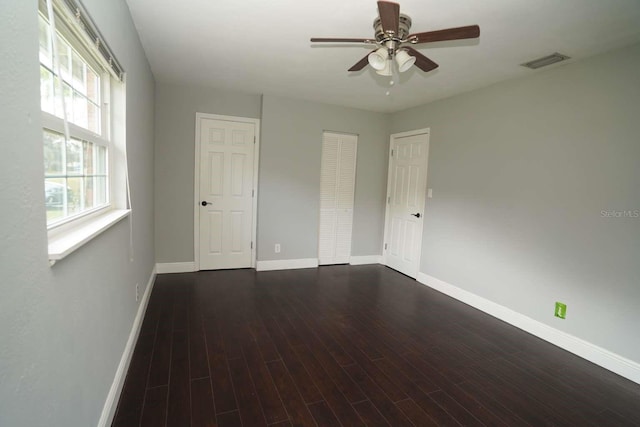 empty room featuring dark wood-type flooring and ceiling fan