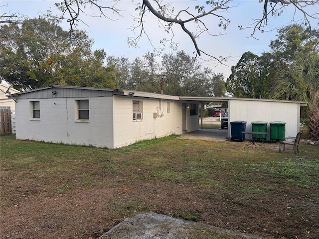 rear view of property featuring cooling unit, a carport, and a yard