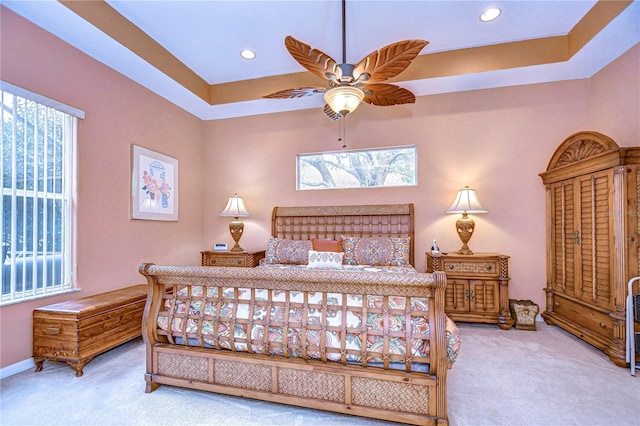 bedroom with multiple windows, carpet, and a tray ceiling