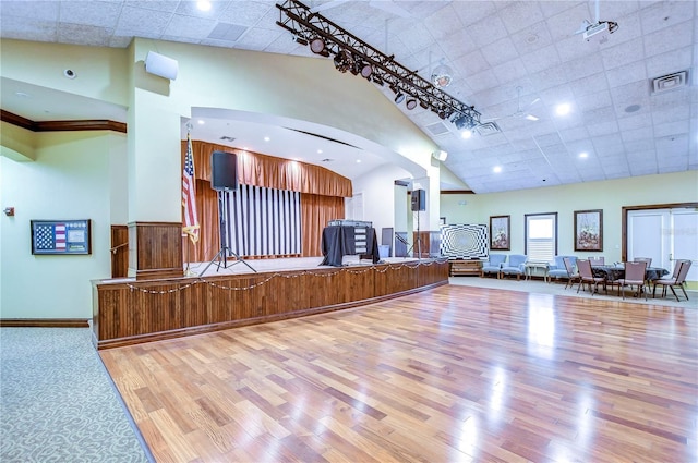 unfurnished living room featuring high vaulted ceiling, decorative columns, and light wood-type flooring