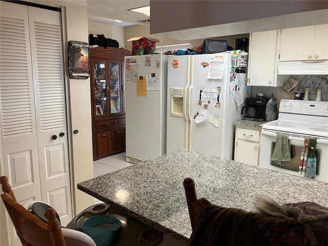 kitchen featuring white appliances, light stone countertops, white cabinets, and light tile patterned flooring