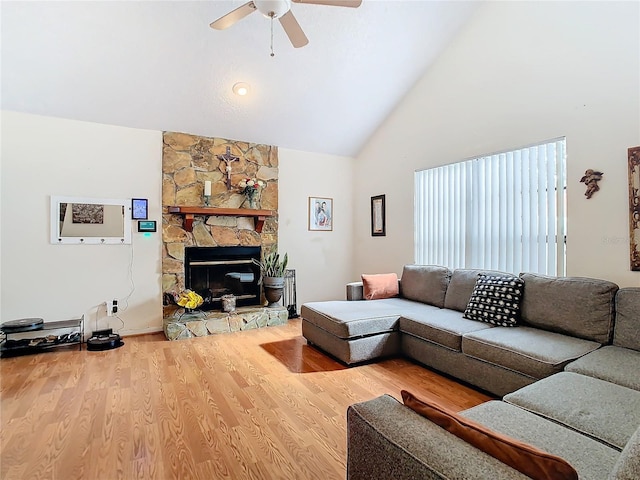 living room with hardwood / wood-style floors, a stone fireplace, high vaulted ceiling, and ceiling fan