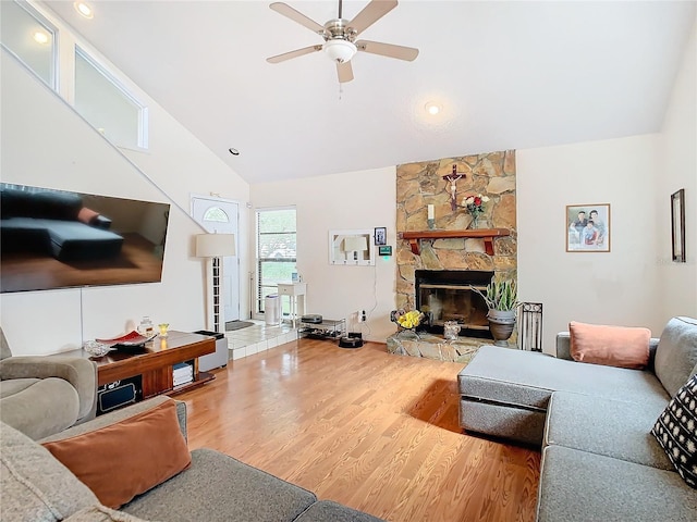 living room with hardwood / wood-style flooring, a stone fireplace, high vaulted ceiling, and ceiling fan