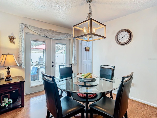 dining area featuring french doors, a chandelier, light hardwood / wood-style flooring, and a textured ceiling