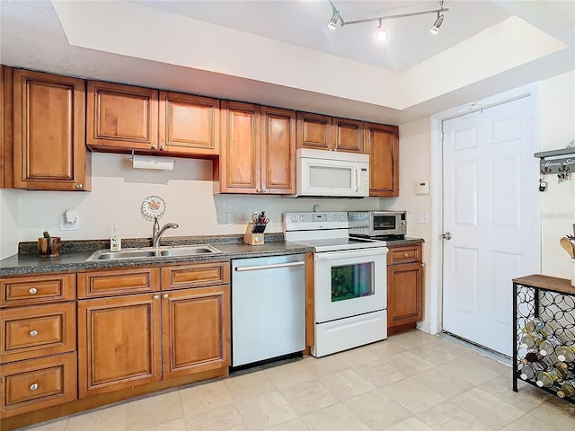 kitchen with a tray ceiling, sink, and white appliances