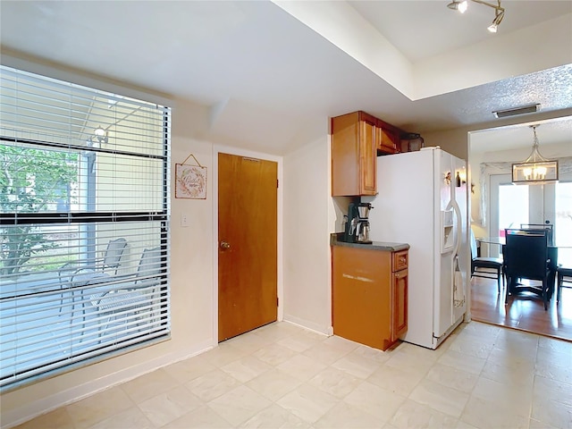 kitchen with a notable chandelier, hanging light fixtures, and white fridge with ice dispenser