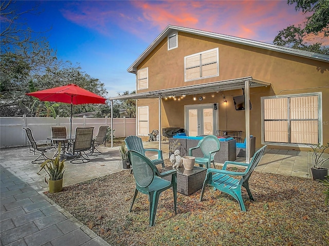 back house at dusk featuring a patio area and french doors