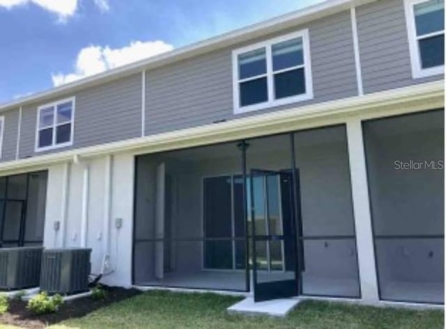 back of property with a sunroom, a yard, and central AC unit