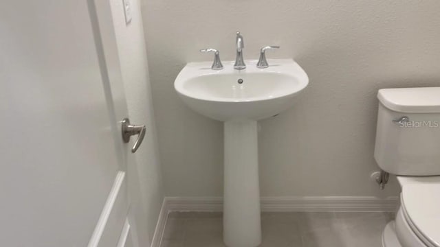 bathroom with toilet, tile patterned flooring, and sink