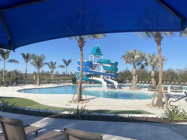 view of swimming pool featuring a water slide and a patio area