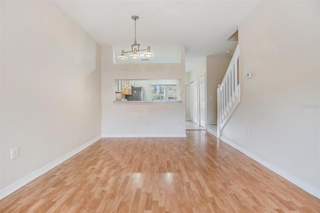 unfurnished living room with light hardwood / wood-style flooring and a notable chandelier