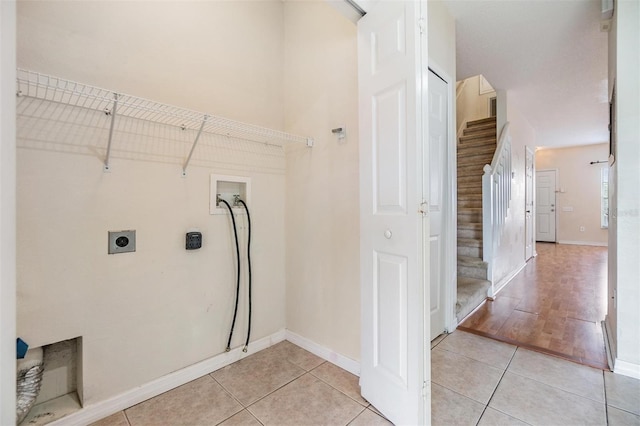 laundry area with electric dryer hookup, hookup for a washing machine, and light tile patterned floors