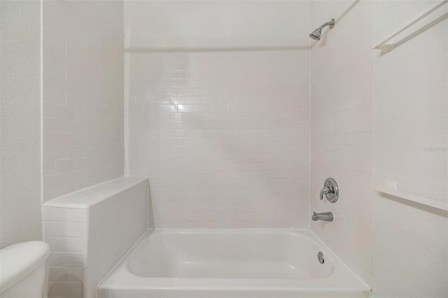 bathroom featuring tiled shower / bath and toilet