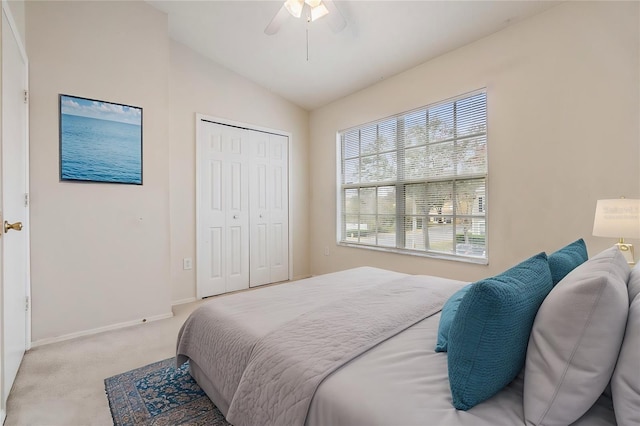 bedroom with vaulted ceiling, light carpet, ceiling fan, and a closet