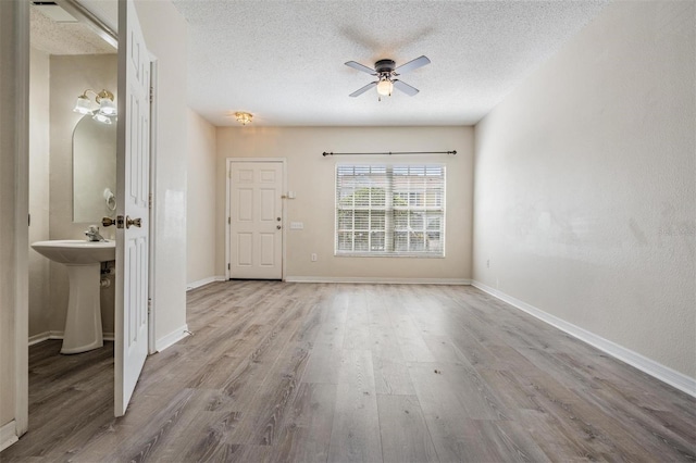 foyer with wood finished floors, a textured ceiling, baseboards, and ceiling fan