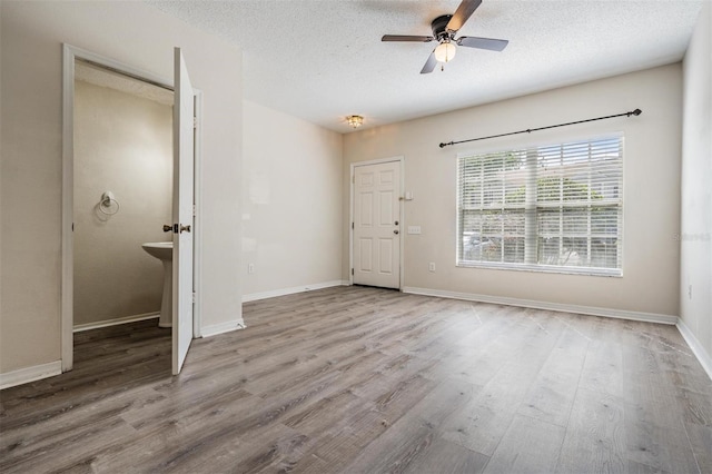 interior space featuring a textured ceiling, wood finished floors, a ceiling fan, and baseboards
