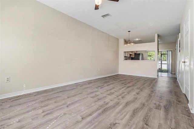 unfurnished living room featuring wood finished floors, visible vents, baseboards, and ceiling fan with notable chandelier