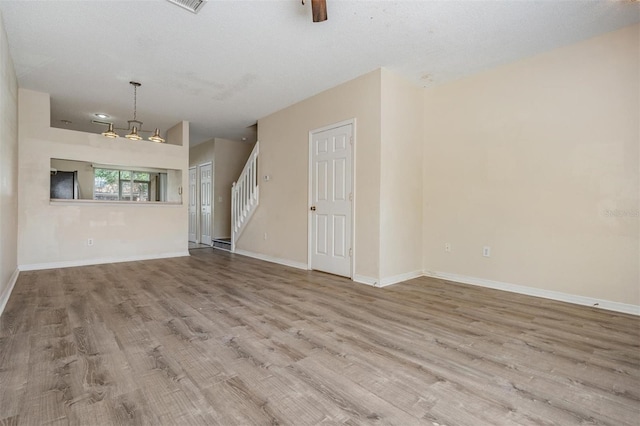 unfurnished living room with wood finished floors, stairs, and baseboards