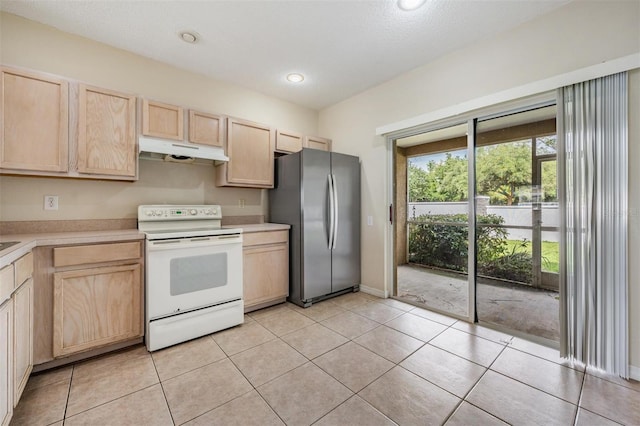 kitchen with electric stove, light brown cabinetry, and freestanding refrigerator