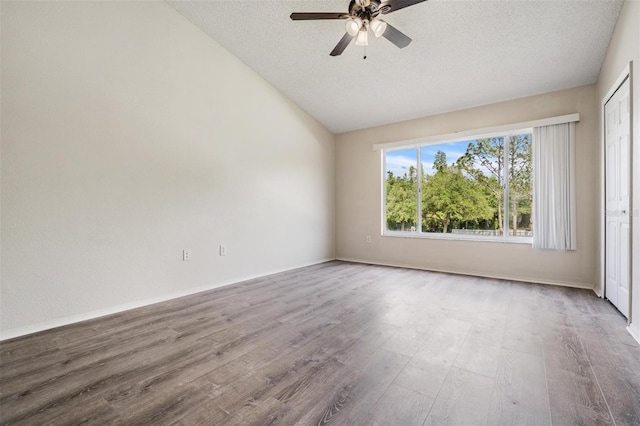 spare room with a ceiling fan, wood finished floors, a textured ceiling, and vaulted ceiling