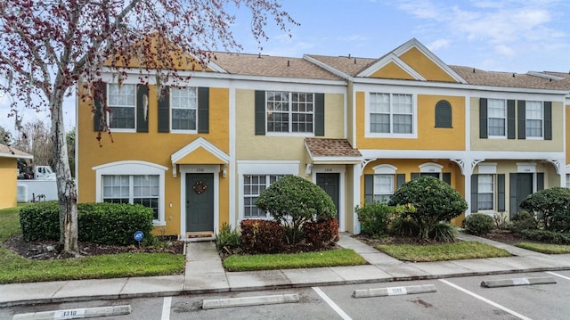 multi unit property featuring stucco siding, a shingled roof, and uncovered parking
